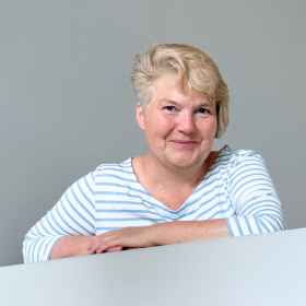 Porträt von Susanne Krüger, mit den Armen auf einer Mauer lehnend